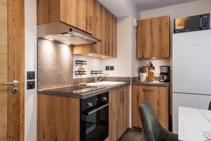 Eine kleine Küche mit Holzausbau, Backofen, Mikrowelle und Spüle.