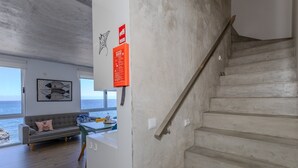 Ein modernes Interieur mit Treppe, Sofa, Tisch und Meerblick.