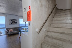 A modern interior with a staircase, a sofa, a table, and a view of the sea. - GuestReady - Pepper of the Sea (Lagoa)
