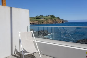 A balcony with a clear view of the ocean and a grassy hill in the background. - GuestReady - Pepper of the Sea (Lagoa)