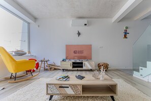 Ein modernes Wohnzimmer mit einem gelben Schaukelstuhl, einem Flachbildfernseher und einem Holztisch.