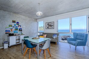A modern kitchen with a dining area, large windows with ocean views, and artwork on the walls.