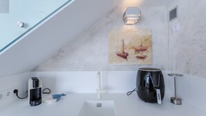Eine moderne Küche mit Kaffeemaschine, Wasserkocher und einem Gemälde von Booten.