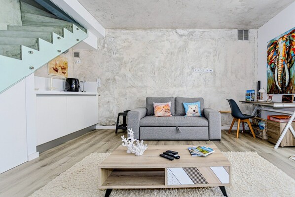 Ein modernes Wohnzimmer mit grauem Sofa, Couchtisch und einem Bild an der Wand.