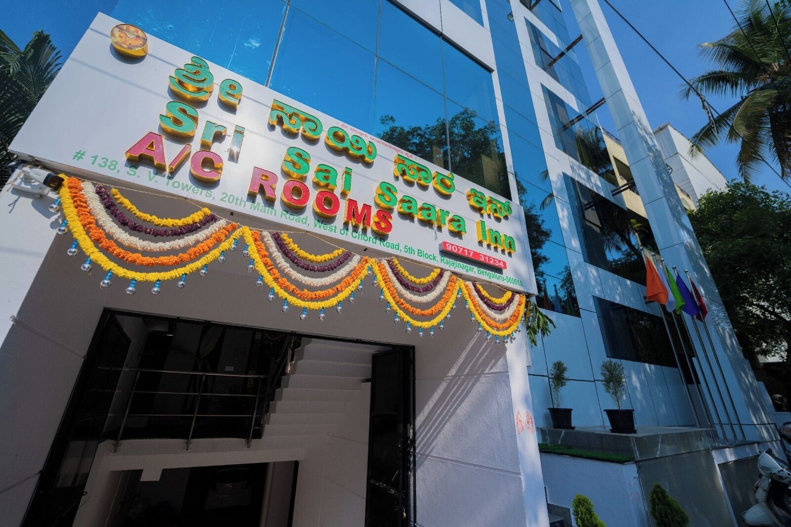 A hotel sign with multi-language text, including English and another language, and a garland of flowers.