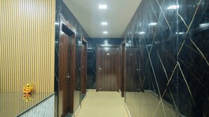 Un pasillo con puertas de madera, un muro de mármol y suelo alfombrado.