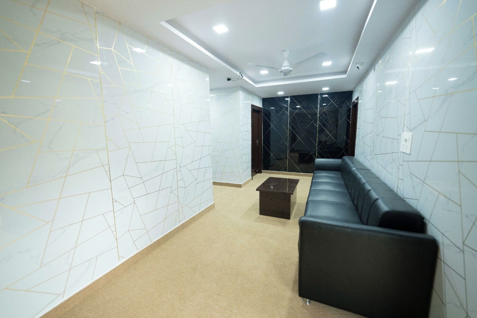 A modern interior with a black leather sofa, a small coffee table, and geometric patterned walls.