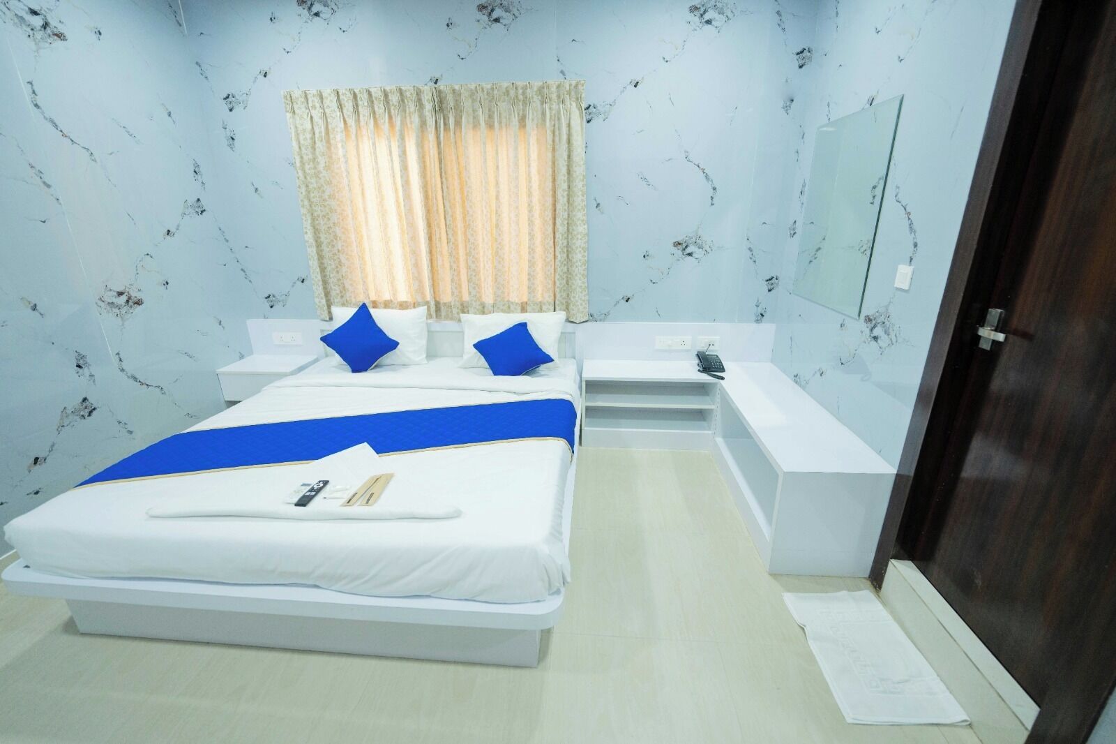 A hotel room with a bed, bedside tables, a desk, a mirror, and a wardrobe.