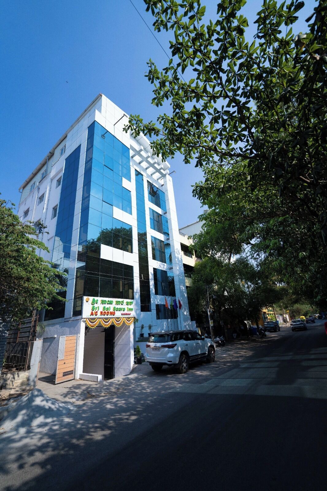 A modern building with glass windows, a signboard, and a parked vehicle.