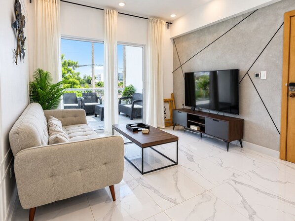 A modern living room with a sofa, coffee table, and a flat-screen TV on a wooden stand.