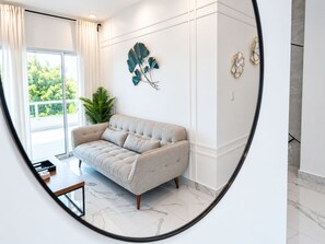 A modern living room with a sofa, a coffee table, and a view of greenery outside.