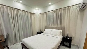 A bedroom with a bed, nightstands, a desk, and curtains. - The Duo by Suarez Properties | Jacuzzi & BBQ (Santo Domingo Este)