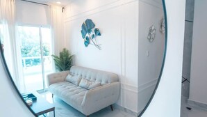 A modern living room with a sofa, a potted plant, and wall art. - The Duo by Suarez Properties | Jacuzzi & BBQ (Santo Domingo Este)