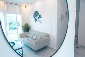 A modern living room with a sofa, a potted plant, and wall art.