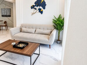 A modern living room with a sofa, a coffee table, a potted plant, and abstract wall art. - The Duo by Suarez Properties | Jacuzzi & BBQ (Santo Domingo Este)
