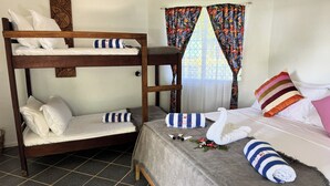 Een slaapkamer met een stapelbed, een grijs bed, witte kussens en gestreepte kussens.