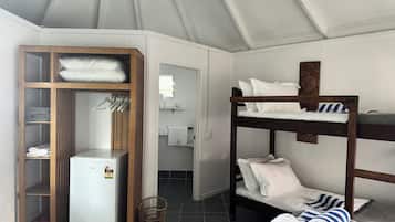 A compact room with a bunk bed, a wardrobe, a small refrigerator, and a tiled floor.