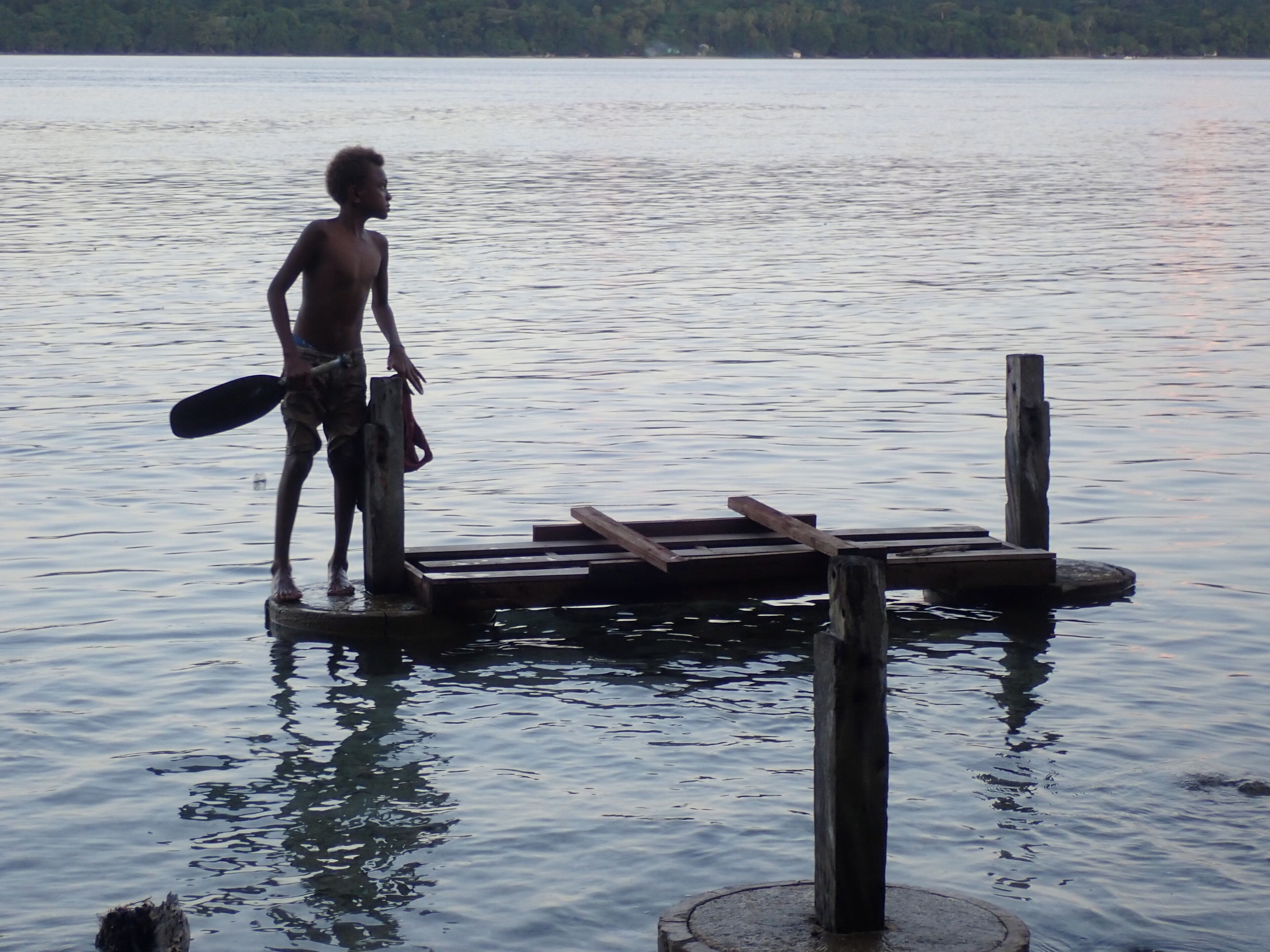Una persona in piedi su un molo di legno che si protende in un corpo d'acqua.