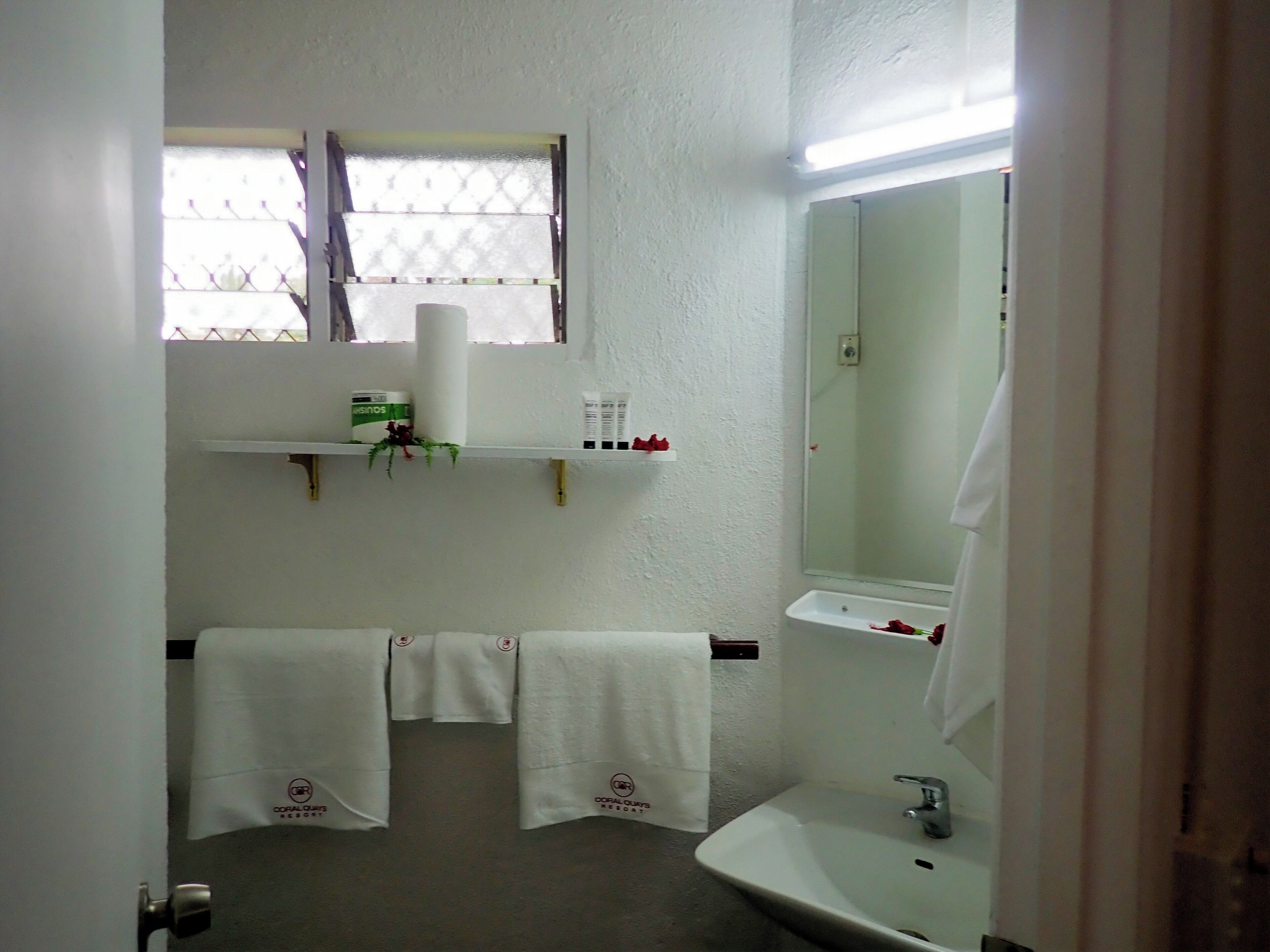 A bathroom with a sink, mirror, towel rack, and a window with a curtain.