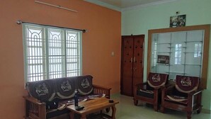 A room with a sofa set, a wooden table, a cabinet with glass doors, and a window with bars.
