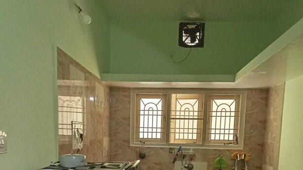 A compact kitchen with a refrigerator, a sink, and a window with bars.