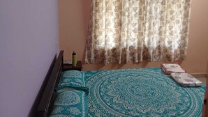 A bedroom with a bed, a hanging curtain, and a bedside table with a water bottle.