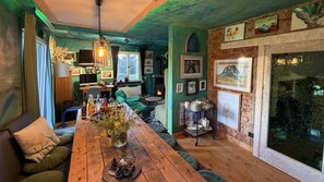 A cozy room with a wooden table, green sofa, and a fireplace.