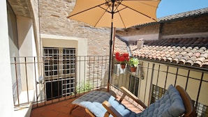 A balcony with a cushioned chair, a large umbrella, and potted plants. - Dimora Castracane - House in historic building from 1400 with cloister, balcony and private parking space (Fano)