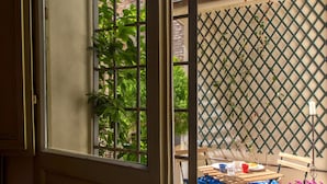 A room with a window, a table with chairs, and a lattice wall. - Dimora Castracane - House in historic building from 1400 with cloister, balcony and private parking space (Fano)