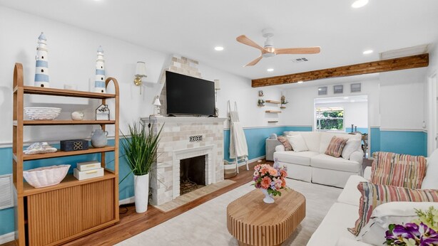 Ein modernes Wohnzimmer mit Kamin, Fernseher, Holzregal und weißem Sofa.