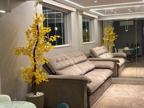 Uma sala de estar moderna com um sofá, um vaso de planta e uma área de jantar.