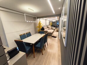 Interior moderno com área de refeições, sofás e cozinha.