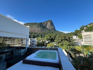 Terraço com banheira de hidromassagem, espaço para cozinha e vista para uma montanha.