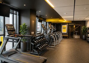 Une salle de sport équipée de tapis de course, d’haltères et d’appareils d’entraînement.
