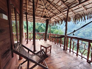 A wooden deck with a thatched roof, a hammock, and a bench. - Ella Treehouse (Ella)