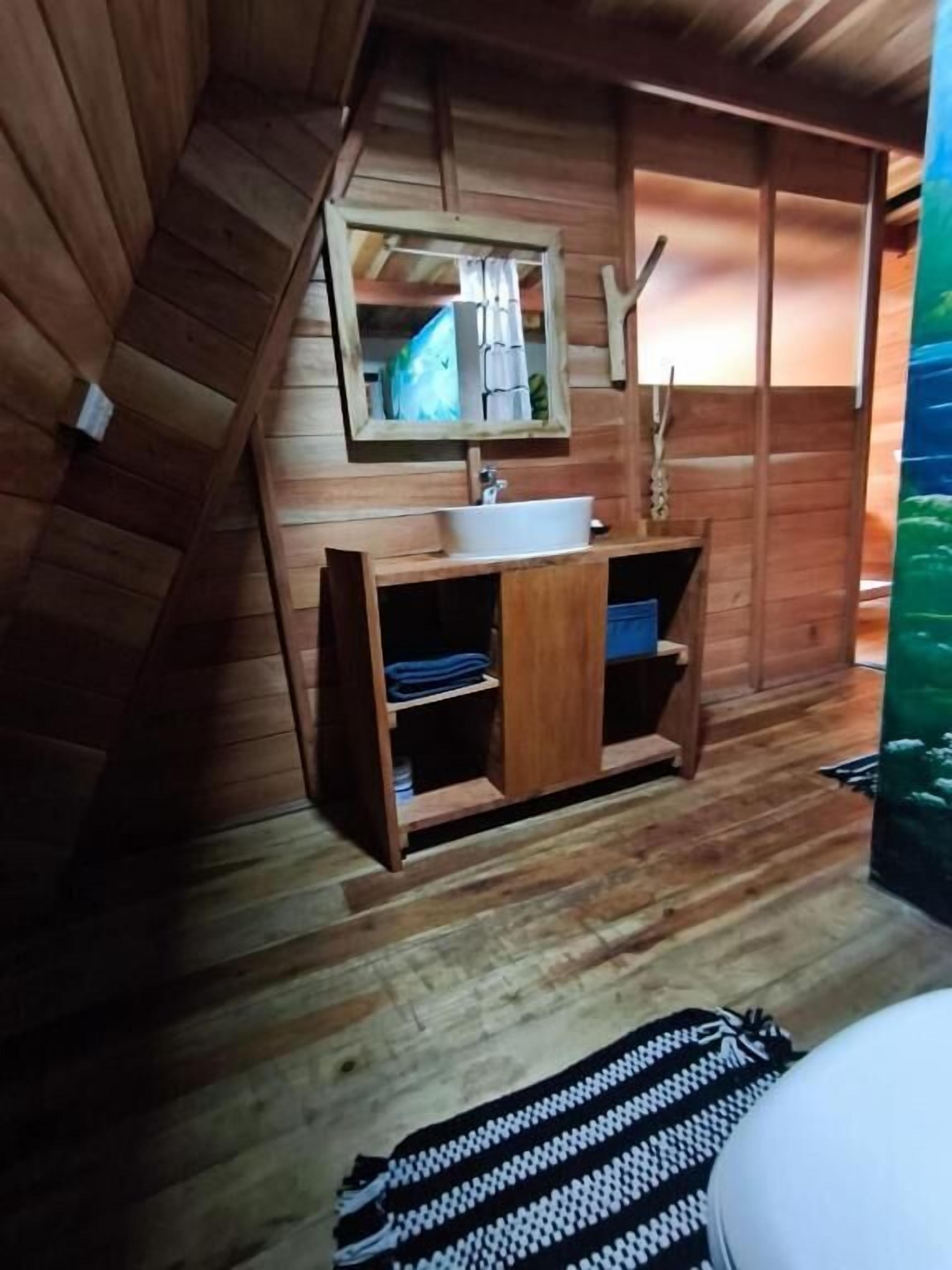 A wooden cabin-style bathroom with a wooden vanity, a mirror, and a sink.