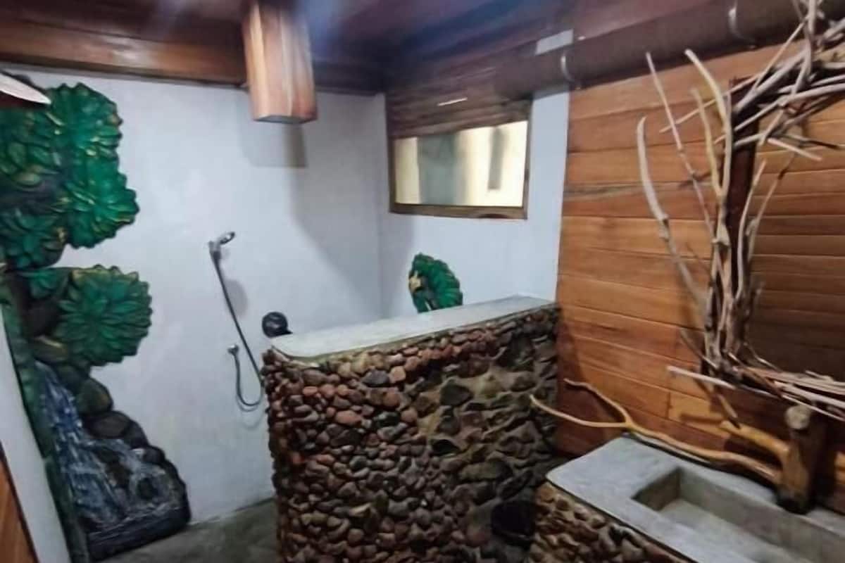 Un baño con pared de piedra, techo de madera y un espejo.