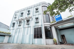 A modern building with a blue and white facade, a sign for 'Rehat Sentra Inn,' and a potted plant near the entrance. - Rehat at Sentra Inn Bandung (Bandung)