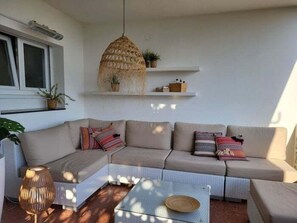 A modern living room with a sectional sofa, a glass coffee table, and a hanging rattan light fixture. - Condo in Roses · ★4.68 (Roses)
