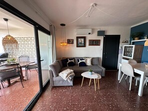 A modern living room with a sofa, coffee table, dining table, and chairs. - Condo in Roses · ★4.68 (Roses)