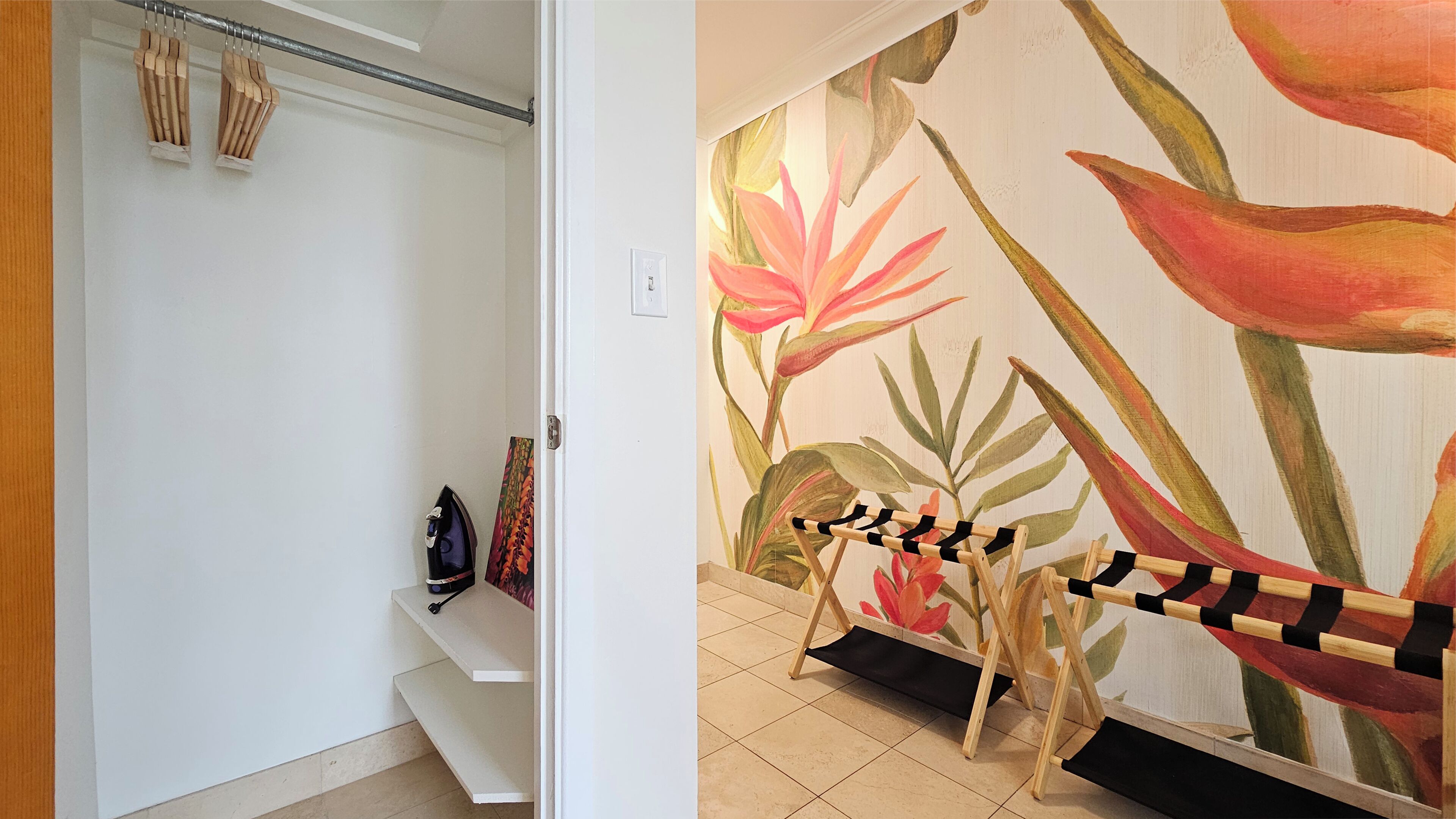 A hallway with a staircase, a wooden ironing board, and a floral wall mural.