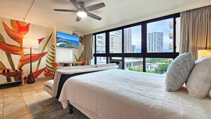 A hotel room with a bed, a ceiling fan, a TV, and a large window with a city view. - NEW 2026 Renovated Studio— Sleeps 3—Limited Dates—Near Waikiki Beach ●WG 519● (Honolulu)