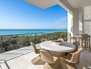 Una mesa redonda con sillas de mimbre en un balcón con vistas al mar.