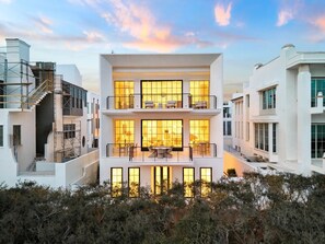 Un edificio moderno de dos plantas con ventanas amplias, un balcón y una escalera.