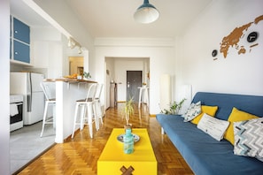 A modern living room with a blue sofa, yellow ottoman, and a wooden coffee table. - Amazing Acropolis View From A Sunny Renovated Apt in Athens! (Athina)