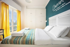 A hotel room with a bed, curtains, a wardrobe, and a wall with a quote. - Amazing Acropolis View From A Sunny Renovated Apt in Athens! (Athina)