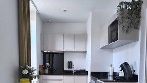 A modern kitchen with white cabinets, a dining table with yellow chairs, and a small island with a coffee machine. - Le Yellow: Design Studio, Fibre, Metz Center (Metz)