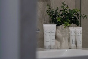 Three Ozone shower gel bottles on a bathroom counter with a potted plant in the background. - Bright Studio | Balcony | Close to PGE Narodowy (Warszawa)