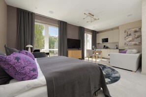 Une chambre d’hôtel moderne équipée d’un grand lit, d’un bureau, d’un canapé, d’une télévision et d’un coin repas.