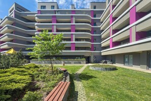 A multi-story residential building with balconies, a paved pathway, and a small tree. - Family Apartment in Wroclaw | Balcony | Parking | 2 Bedrooms (Wrocław)